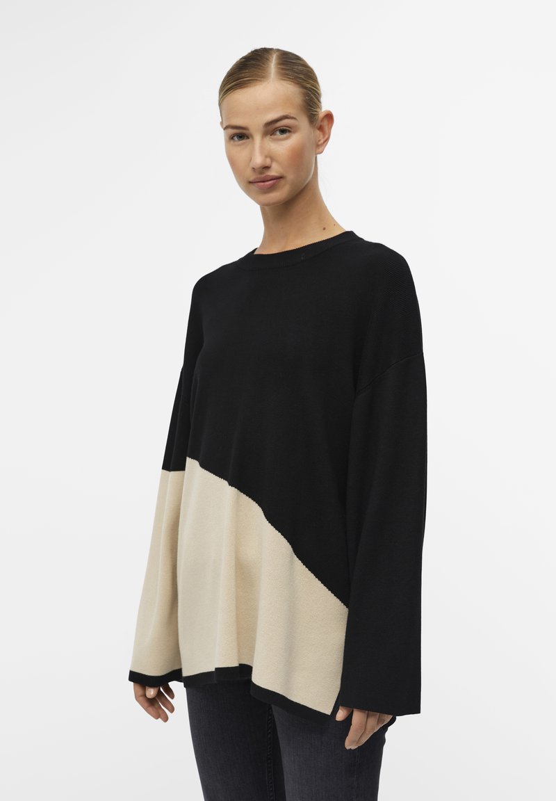 Maglione in blocchi di colore nero e crema con una vestibilità ampia e rilassata, dotato di un colletto a coste e maniche lunghe. Texture morbida.