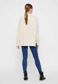 Beige Cordhemd mit einem Rückenpasse, lässiger Schnitt und langen Ärmeln, kombiniert mit blauen Skinny Jeans und schwarzen Stiefeletten.