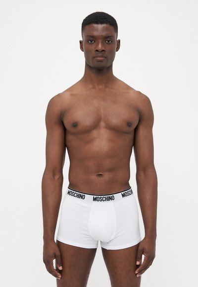 White boxer shorts with a black Moschino logo waistband, made of stretch cotton, featuring a snug fit and smooth texture.