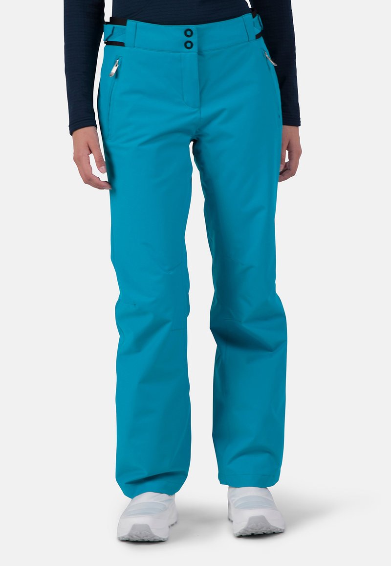 Turquoise skibroek met een rechte snit, twee voorkruiszakken en zwarte riemdetails. Gemaakt van een gladde, weersbestendige stof.