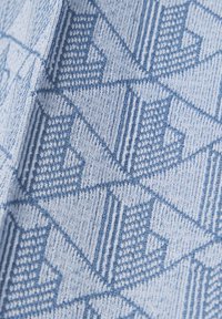 Lichtblauwe stof met geweven geometrisch patroon van donkerblauwe driehoeken en diagonale lijnen in een terugkerend ontwerp.