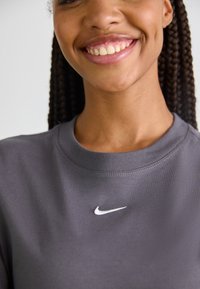 Grå hettegenser med rund hals, myk stoff, med en hvit Nike-logo på brystet, som fremhever et enkelt og minimalistisk design.