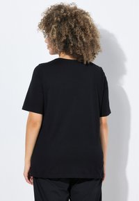Camiseta negra de ajuste relajado, con mangas cortas y cuello redondo. Fabricada en una tela suave, presenta una textura lisa sin patrones.
