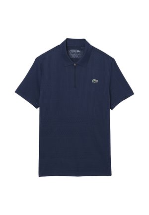 Polo de manga corta azul marino con media cremallera y pequeño logo de cocodrilo verde en el pecho izquierdo.