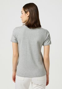 Camiseta de algodón gris con cuello redondo, mangas cortas y un ajuste relajado. Textura suave con un sutil patrón jaspeado, sin logos visibles.