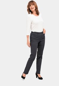 Rekbare zwarte broek met een elastische tailleband, zijzakken, een getailleerde pasvorm en een zachte textuur, gecombineerd met een wit long-sleeve shirt.