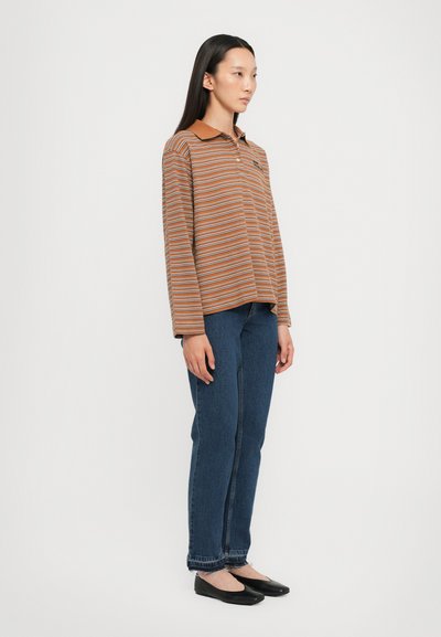 Long-sleeve, brown and orange striped polo shirt with a collar, paired with dark blue straight-leg jeans and black flat shoes.
