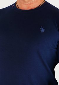 T-shirt in cotone blu navy con collo rotondo, dotato di un logo ricamato tonale discreto sul petto e un dettaglio a contrasto sul collo.