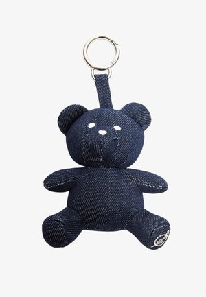 Portachiavi a forma di orsetto in denim con orecchie rotonde, caratteristiche ricamate e anello in metallo argentato. Tessuto blu scuro con sottili righe verticali e una piccola etichetta con logo.