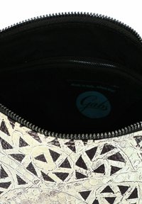 Witte en zwarte leren tas met geometrisch patroon, met ritssluiting en een zachte zwarte stoffen binnenkant. Label aan de binnenkant zegt "Gabs."