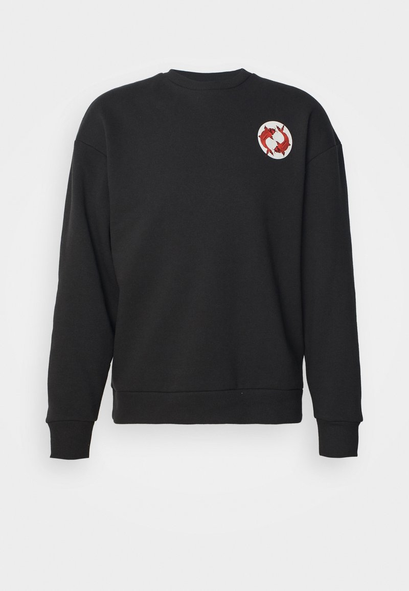 Svart sweatshirt med en rund röd och vit broderad patch med fiskdesign, långa ärmar och ribbade mudd och nederkant.
