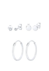 Ensemble de boucles d'oreilles en argent comprenant deux paires de clous d'oreilles (une simple, une avec une pierre transparente) et une paire de boucles d'oreilles créoles avec une finition lisse.