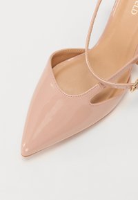 Spiss tå, rosa patentlærsko med utskjæringsdesign og ankelstropp. Glatt tekstur med en lett glans.