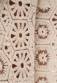 Μπεζ δαντέλα με πολύπλοκα εξαγωνικά μοτίβα και λουλούδια, με υφή και ανοιχτό πλεκτό σχέδιο.