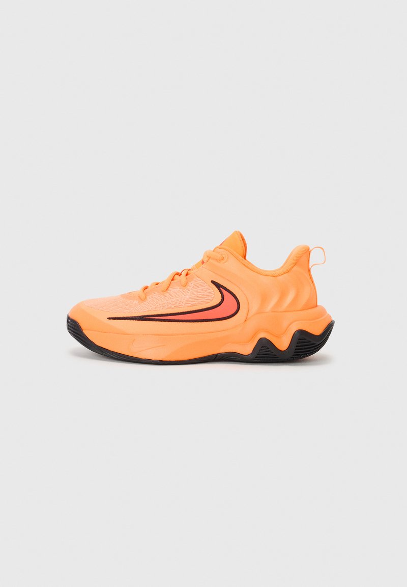 Basket de sport Nike en orange vif, avec une tige texturée, une semelle noire, des accents de design courbés et une languette au talon.