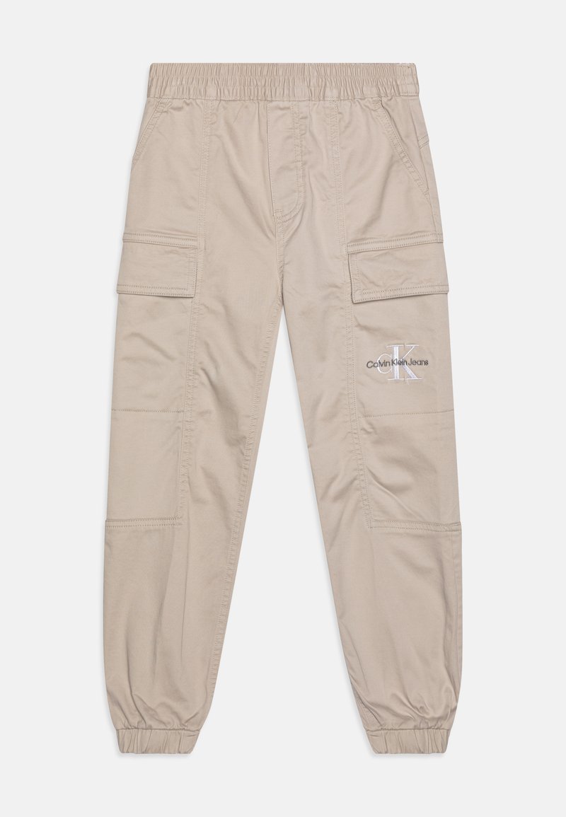 Béžové cargo nohavice s elastickým pásom, bočnými vreckami a elastickými manžetami; na prednej strane sa nachádza logo Calvin Klein Jeans.
