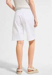 Valkoiset puuvillabermudashortsit, joissa on rento istuvuus, kaksi takataskua ja sileä pinta. Yhdistetty neutraalinsävyisiin sandaaleihin.