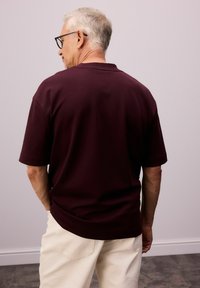 Bordeaux kortærmet polo-shirt med en afslappet pasform, lavet af glat stof, med en klassisk krave og diskrete syningsdetaljer.