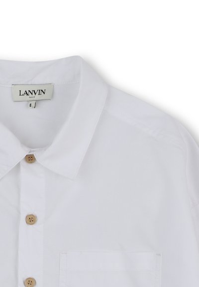 Camicia bianca in cotone con colletto a punta, bottoni in legno, taschino sul petto e tessuto di cotone liscio. Etichetta del marchio visibile.
