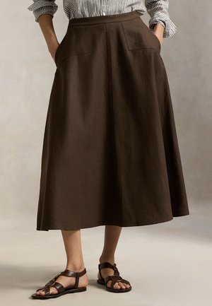 Pruun linane midi-seelik küljetaskute, lameda vööotsa ja õrna tekstuuriga. Kombineeritud tumepruunide rihmikandadega sandaalidega.