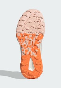 Shoe outsole featuring a textured pink rubber base with an orange traction pattern, designed for durability and grip on various surfaces.