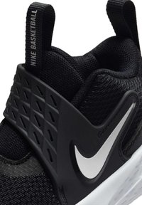 Chaussure de basketball Nike noire avec logo swoosh blanc, tige en mesh texturé et languette au talon portant l’inscription "NIKE BASKETBALL".
