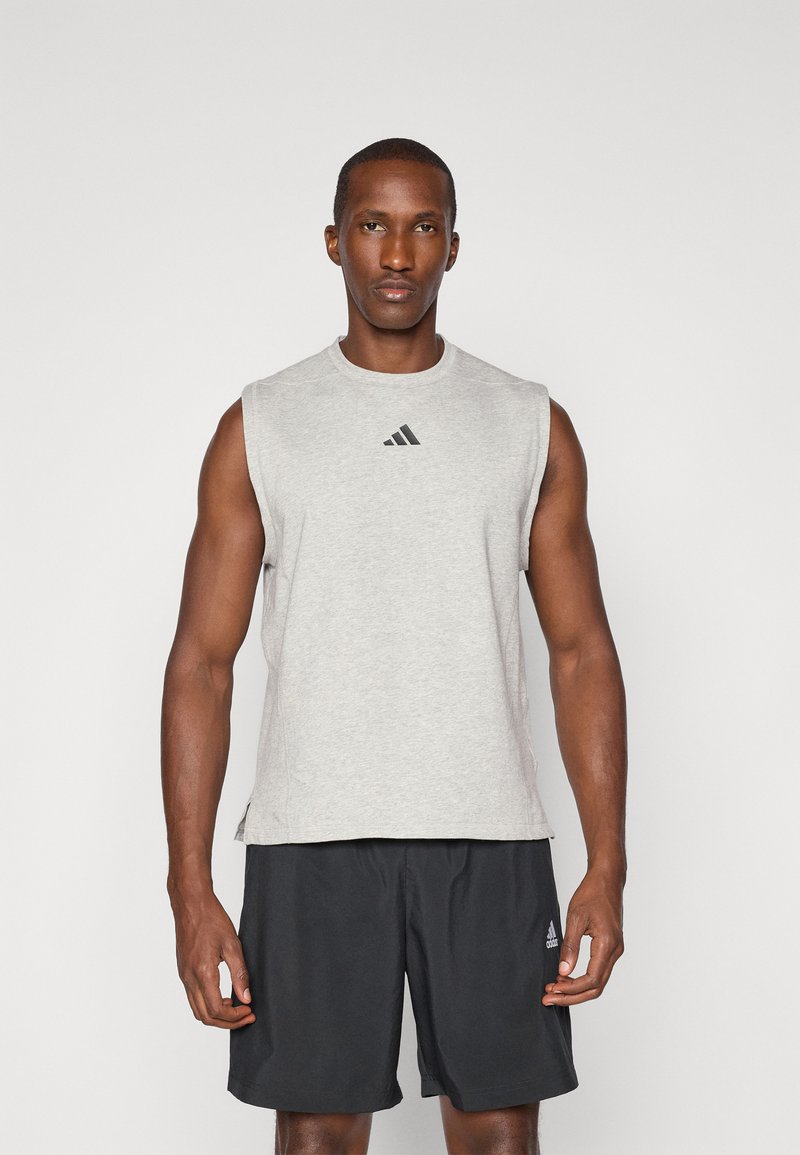 T-shirt de sport sans manches gris avec un col rond et le logo Adidas noir, associé à un short noir. Tissu lisse avec une coupe décontractée.