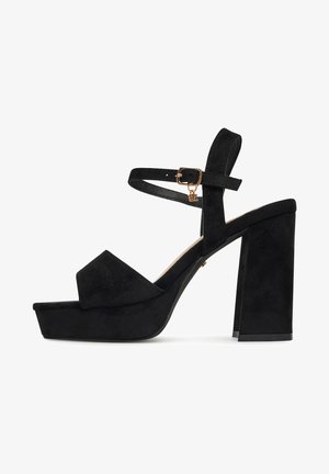 Sandalo con zeppa in camoscio nero, tacco a blocco, cinturino alla caviglia e fibbia dorata con piccolo ciondolo a forma di lettera.
