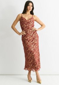 Maxi dress in burgundy with a floral leopard print, crafted from lightweight fabric, featuring adjustable straps and a flowy hem.