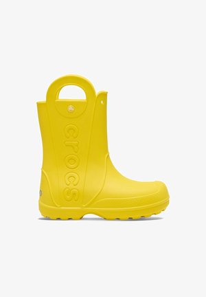 Geel rubberen regenlaars met een gestructureerde zool, verhoogd "crocs" logo aan de zijkant en een ronde handgreep bovenaan voor gemakkelijk aantrekken.