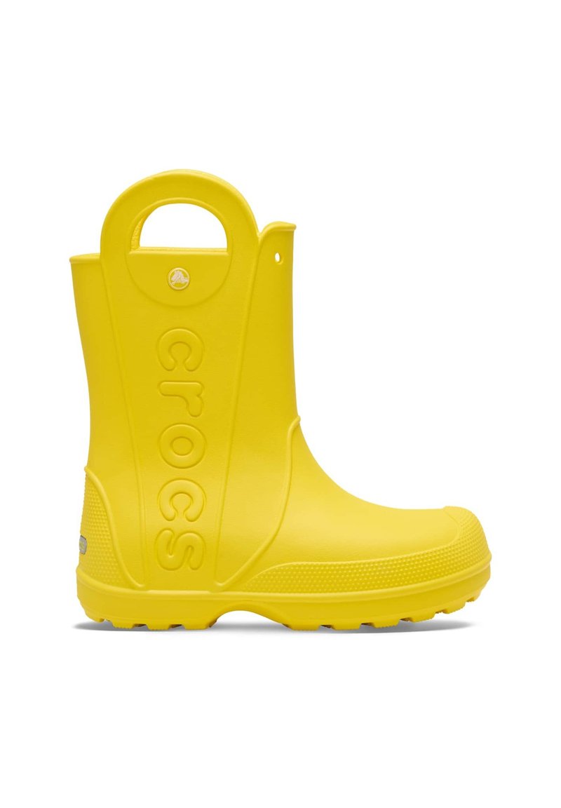 Yellow rubber rain boot with a textured sole, raised "crocs" logo on the side, and a circular handle at the top for easy pull-on.