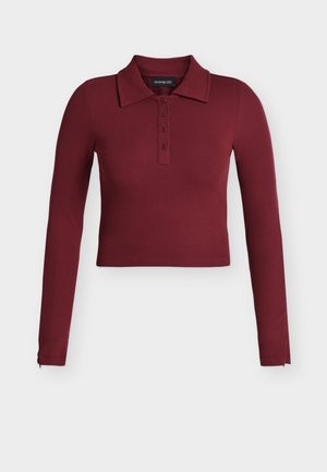 Langermet, ribbestrikket, cropped polo-skjorte i dyp burgunder med krage og fireknappers knepping.