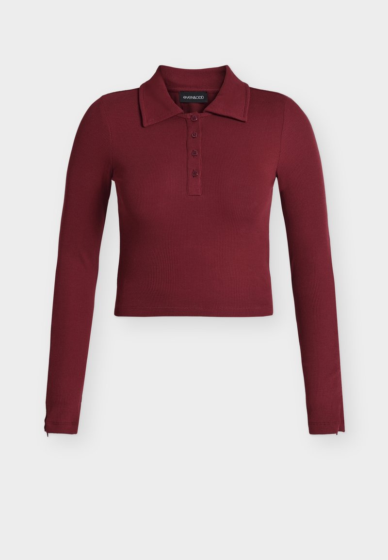 Μακρυμάνικη, με ριπ ύφανση, κοντή πόλο μπλούζα σε βαθύ βουργουνδί χρώμα με γιακά και λωρίδα με τέσσερα κουμπιά.