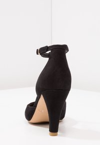 Mustat samettiset korkokengät, joissa on säädettävä nilkkaremmi ja 3-tuumainen korko. Sileä pinta, terävä kärki ja avoimet sivut.