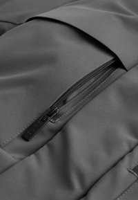 Zwarte stoffen rugzak met een soepele textuur, een ritsvak aan de voorkant en een eenvoudig ontwerp met strakke lijnen.