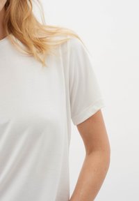 Tricou alb cu mânecă scurtă, realizat dintr-un material moale și ușor. Prezintă un decolteu clasic în formă de cerc și o croială lejeră. Textură netedă.