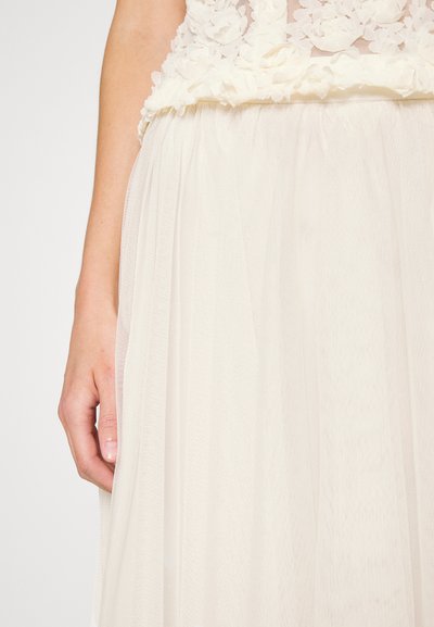 Rochie albă cu un corset din dantelă florală și o fustă din tul transparent, fluidă. Textura este delicată și ușoară, cu straturi moi.