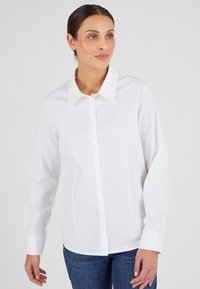 Camisa blanca de botón con cuello estructurado y mangas largas, hecha de tela suave, con corte recto y puños estándar.