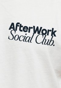 Weißes Baumwoll-T-Shirt mit schwarzem Text, der "AfterWork Social Club" in einer fetten, modernen Schriftart liest. Glatte Textur mit minimalen Details.