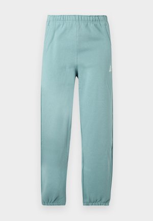 Lys teal joggerbukser lavet af blødt materiale, med elastisk talje, snævre manchetter og en lille logoaccent på siden.