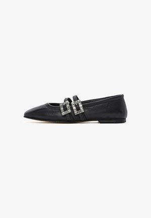 Black leather flat shoe with pointed toe and two straps adorned with rectangular rhinestone buckles, shown in side profile.