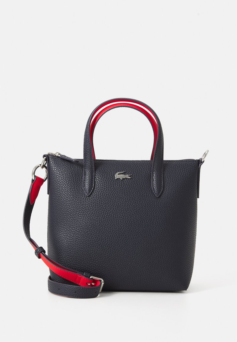 Borsa a tracolla in pelle blu navy con superficie texture, manici corti e una tracolla staccabile rosso e blu navy. Presenta un accento con logo argentato.