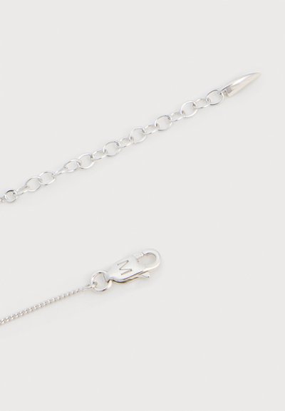 Ασημένιο κολιέ με μικρούς στρογγυλούς κρίκους και κούμπωμα κόμπρας, δίπλα σε ρυθμιζόμενο αλυσίδα με μεγαλύτερους οβάλ κρίκους και τελείωμα σε σχήμα σταγόνας.