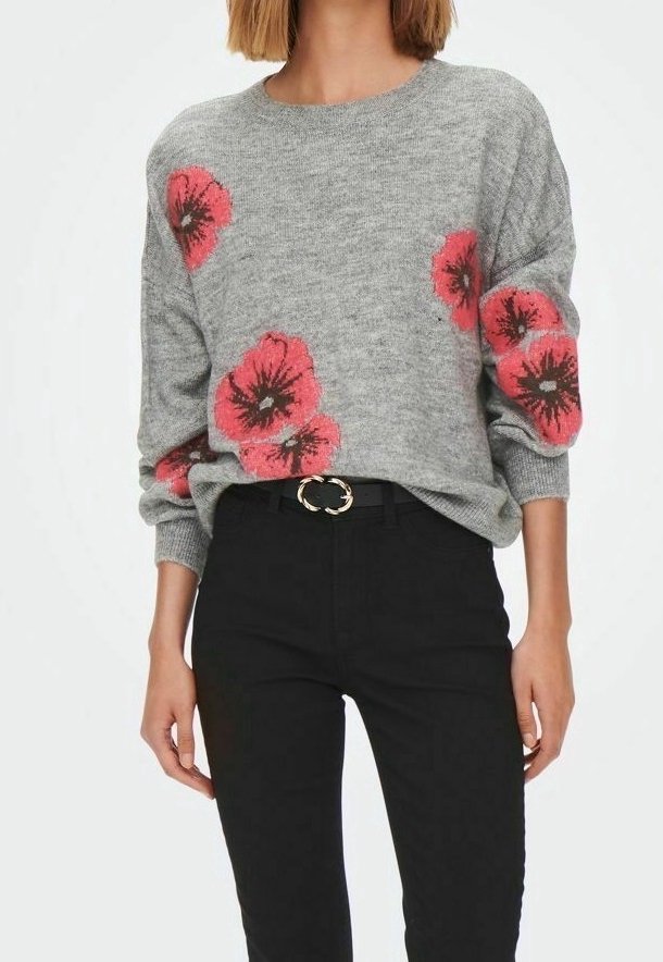 Grauer Strickpullover mit großen roten Blumenmustern, Rundhalsausschnitt und lockerer Passform. Kombiniert mit schwarzen Jeans und einer runden goldenen Gürtelschnalle.