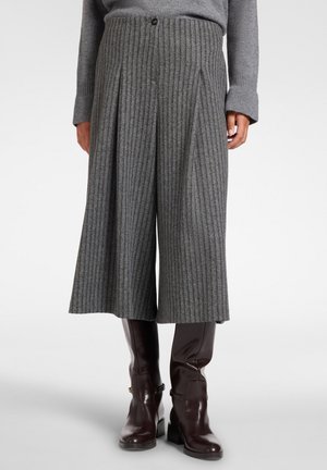 Grå ribstrikkede wide-leg strikkede culottebukser kombineret med mørkebrune knælange læderstøvler på en person iført en matchende grå sweater.