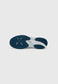 Baskets blanches avec une semelle extérieure texturée bleu marine, présentant des rainures pour la traction et un design épuré. Des accents incluent un logo subtil.