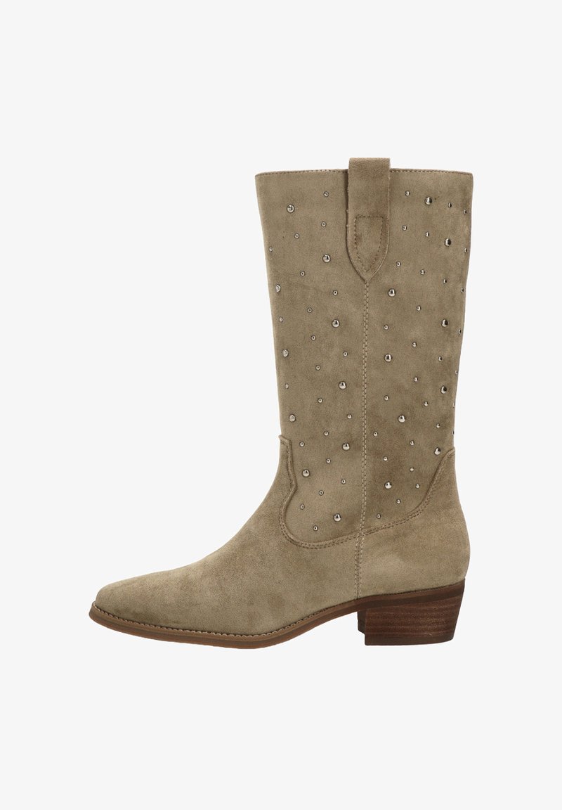 Bota de ante beige hasta la rodilla con punta afilada, adornada con tachuelas plateadas y un tacón de madera apilada. Cuenta con una lengüeta en la parte superior.