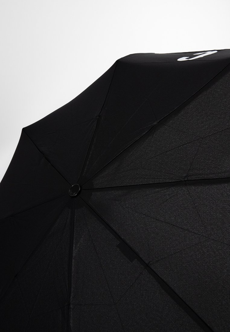 Ombrello nero con una superficie in tessuto liscio, caratterizzato da un rivetto metallico circolare al centro e un design minimalista.