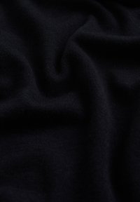 Tissu bleu marine foncé avec une texture douce et lisse, présentant un motif tricoté subtil, tombant en plis délicats.