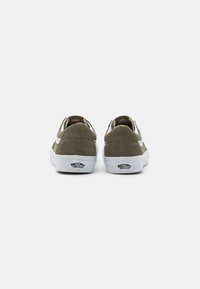 Olivengrønne ruskindssneakers med hvide gummisåler og sidelister. Bagudsigt der fremhæver logo og syninger. Low-top design.